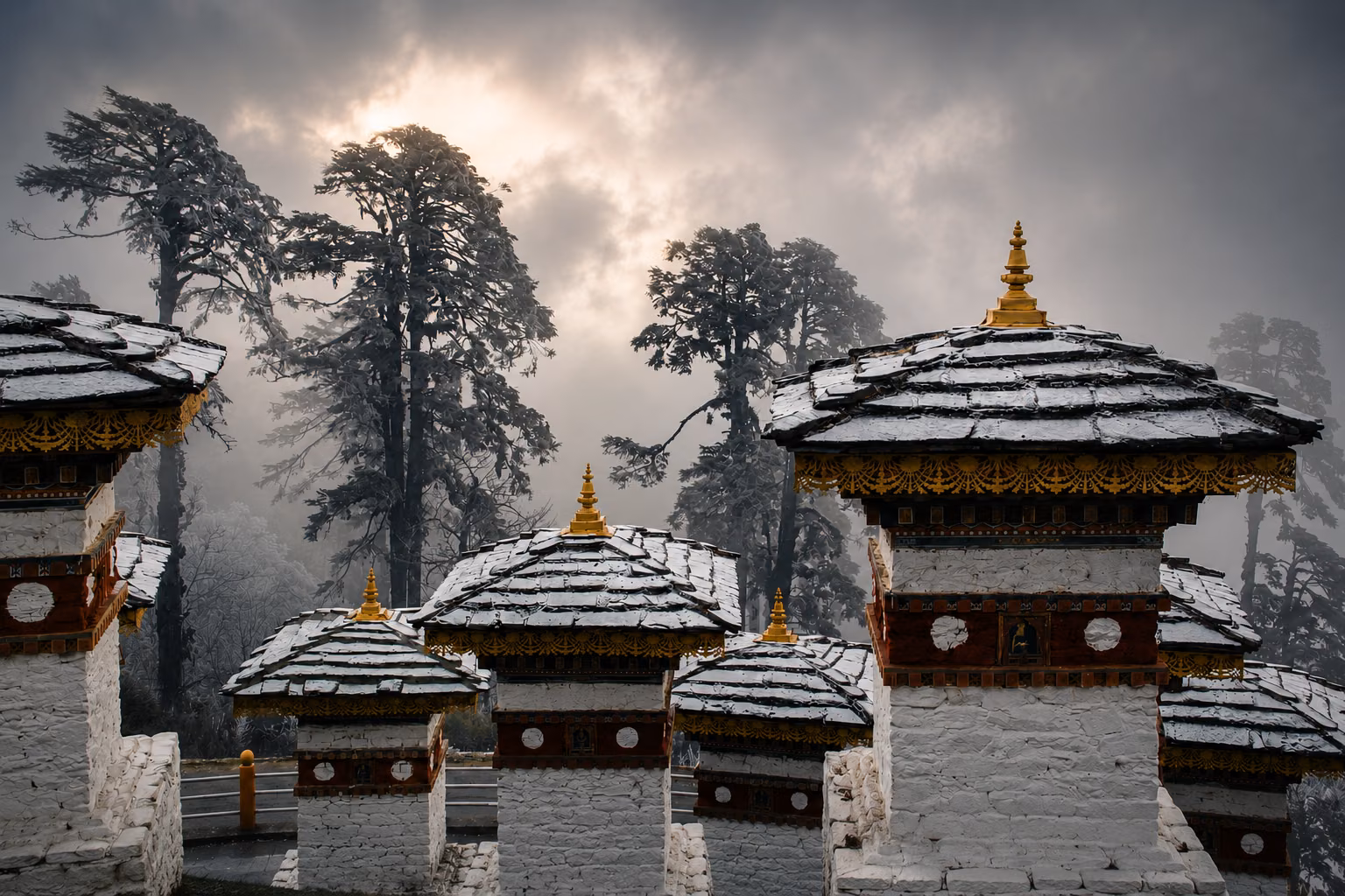 Snow-covered chortens among misty Himalayan trees at Dochula Pass in Bhutan.
