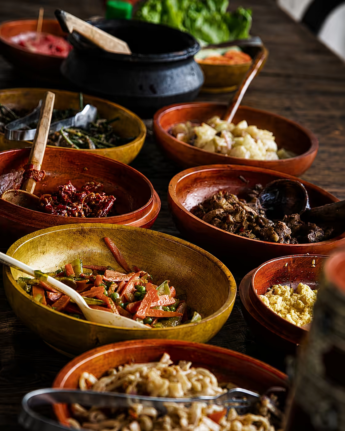 Traditional Bhutanese dishes served in warm wooden bowls on a rustic table.