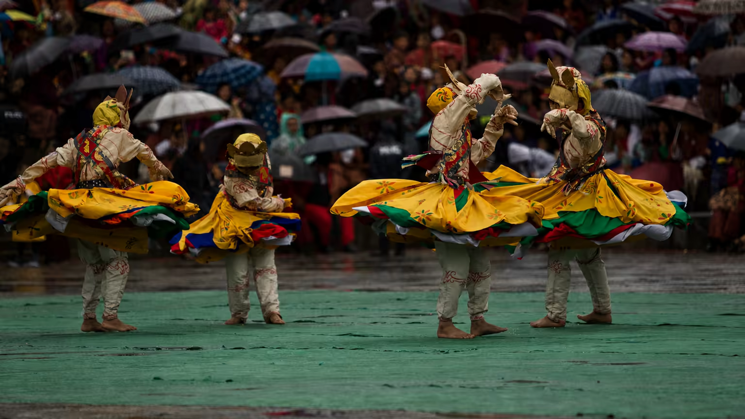 Masked dancers perform during a Bhutanese festival in the rain.