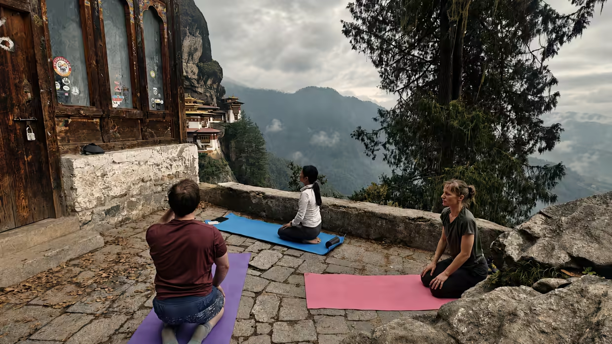 Travellers practise yoga beside a cliffside monastery overlooking Bhutan’s mountains.