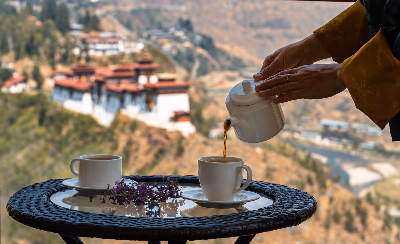 Tea is poured beside a window overlooking a dzong and valley in Bhutan.