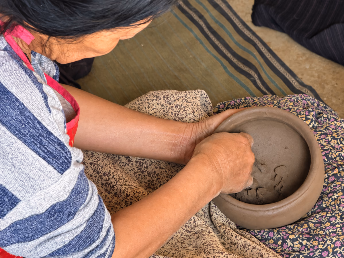 A potter shapes a clay vessel by hand in Gangzur, Bhutan.