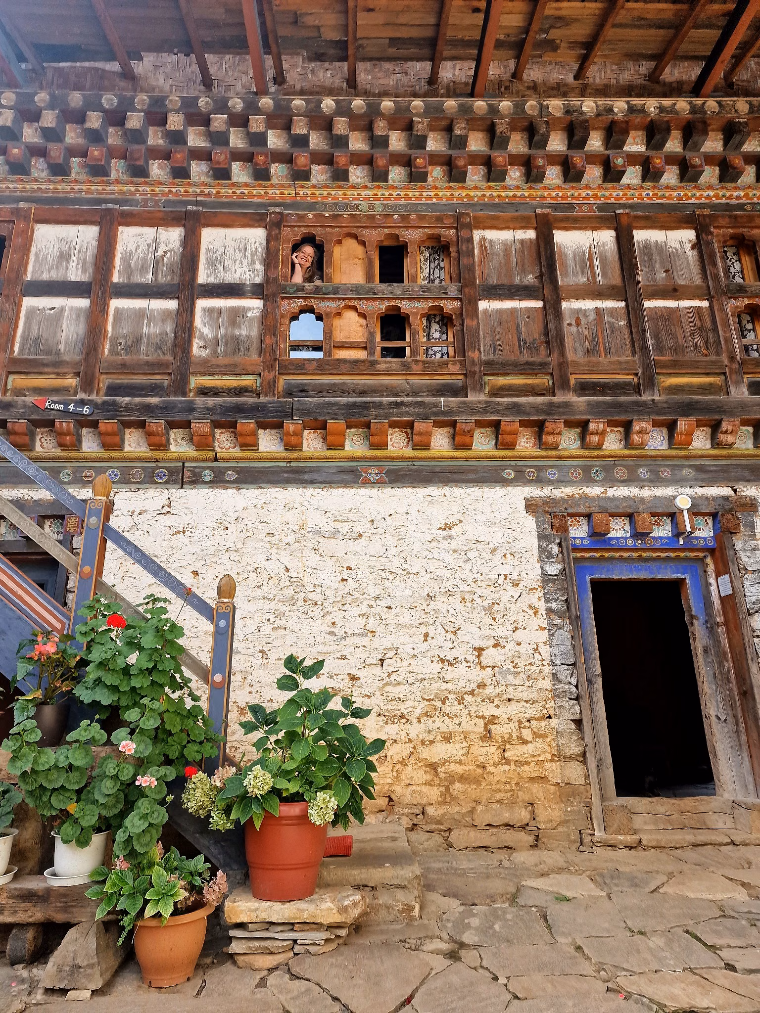 A guest looks out from the upper floor of Ogyen Choling heritage accommodation in Tang Valley, Bumthang.