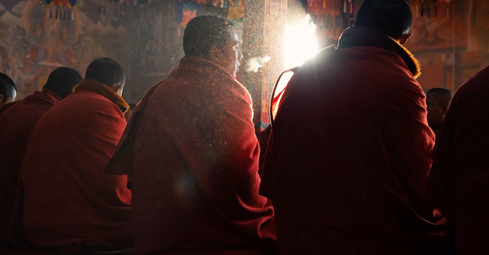 Monks seated inside a Bhutanese monastery as morning light filters through the prayer hall.