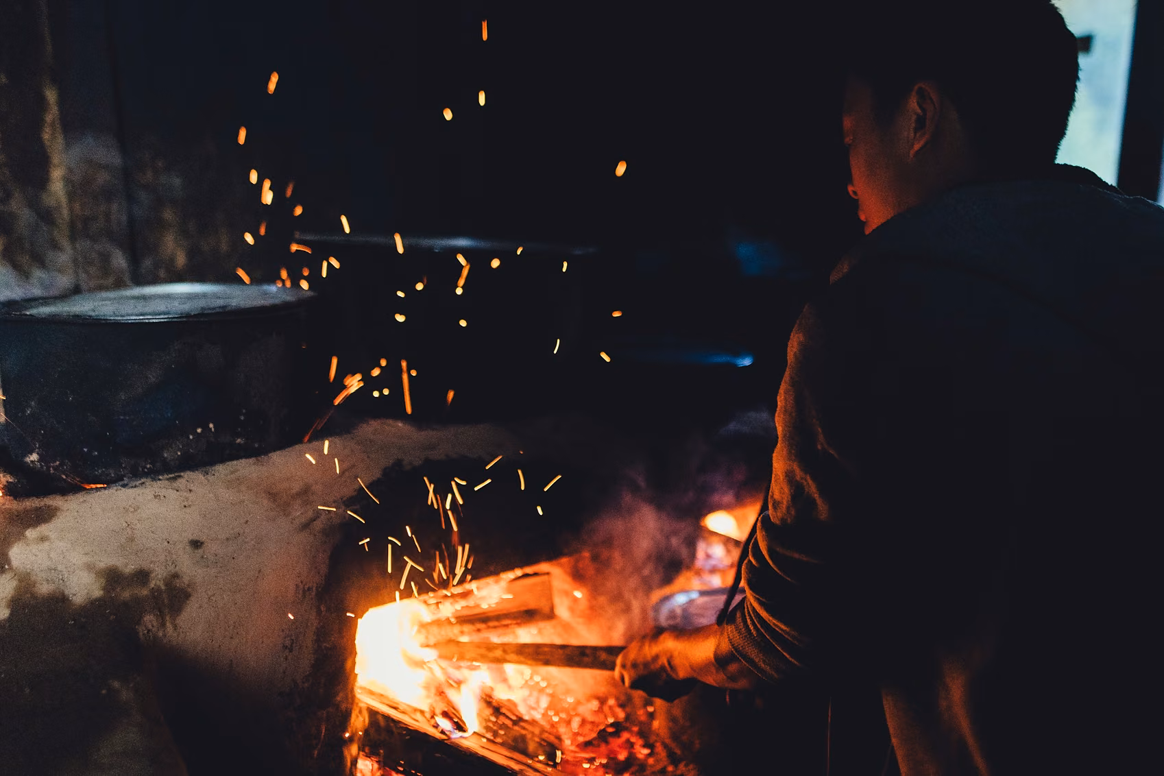A Bhutanese host tends a traditional wood fire during a local food experience.