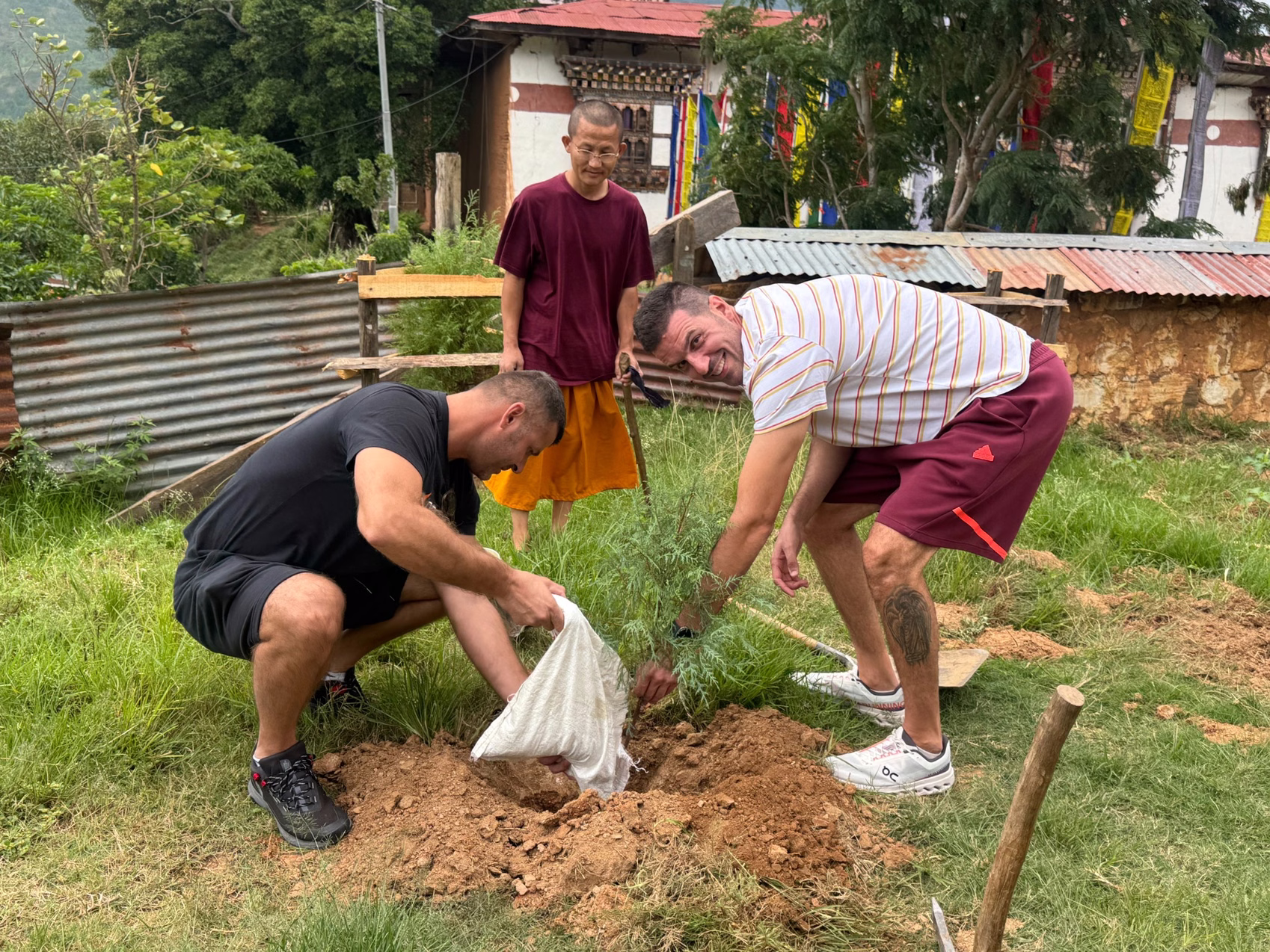 Guests plant a sapling with a monk at Neyzergang Monastery in Punakha.