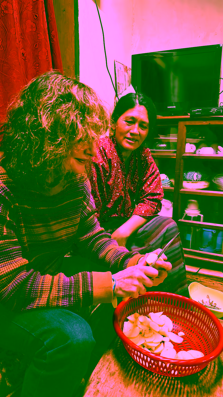 A guest prepares potatoes beside her Bhutanese host during a farmhouse cooking experience in Punakha.
