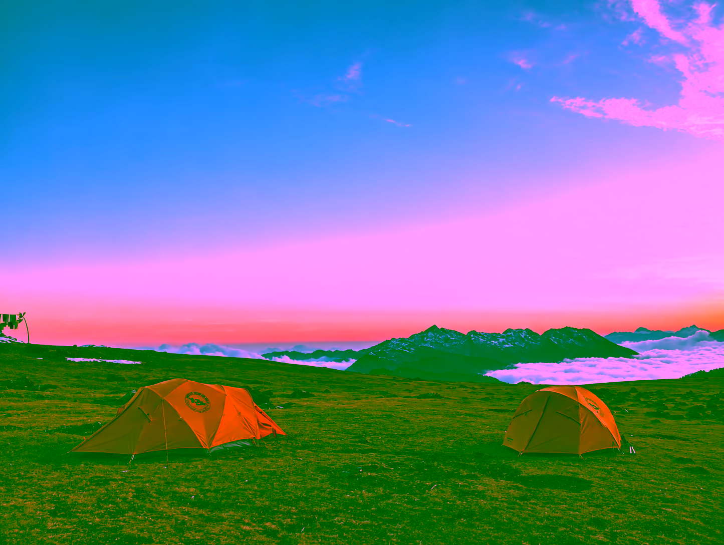 Two orange trekking tents at dusk, overlooking mountain ridges and a sea of clouds in Bhutan.
