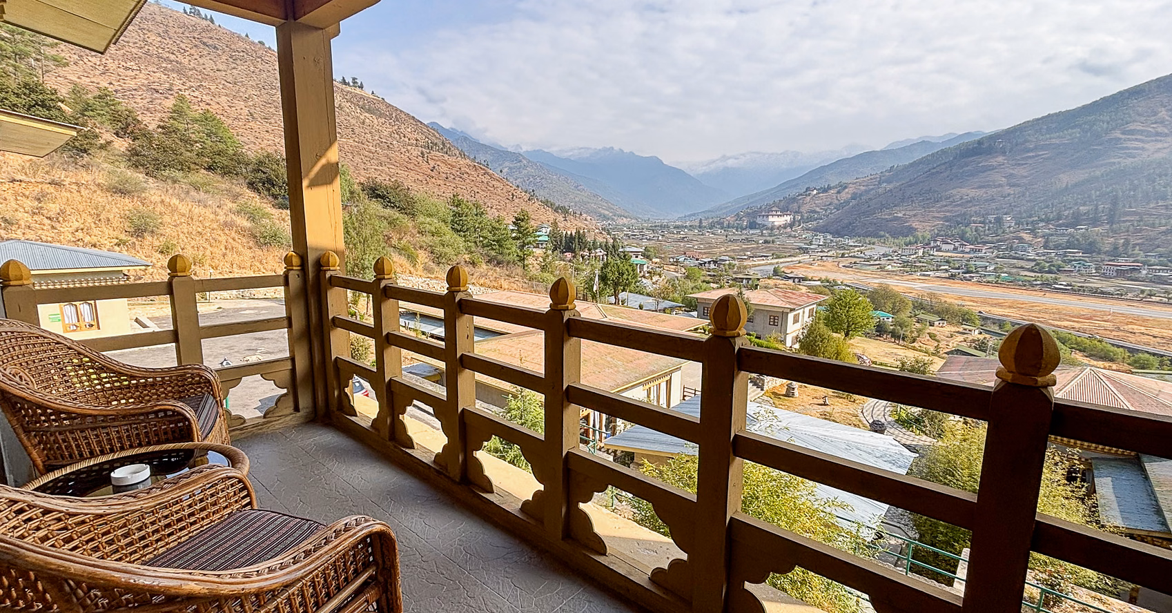 Wicker chairs on a timber balcony overlooking Paro Valley at Khangkhu