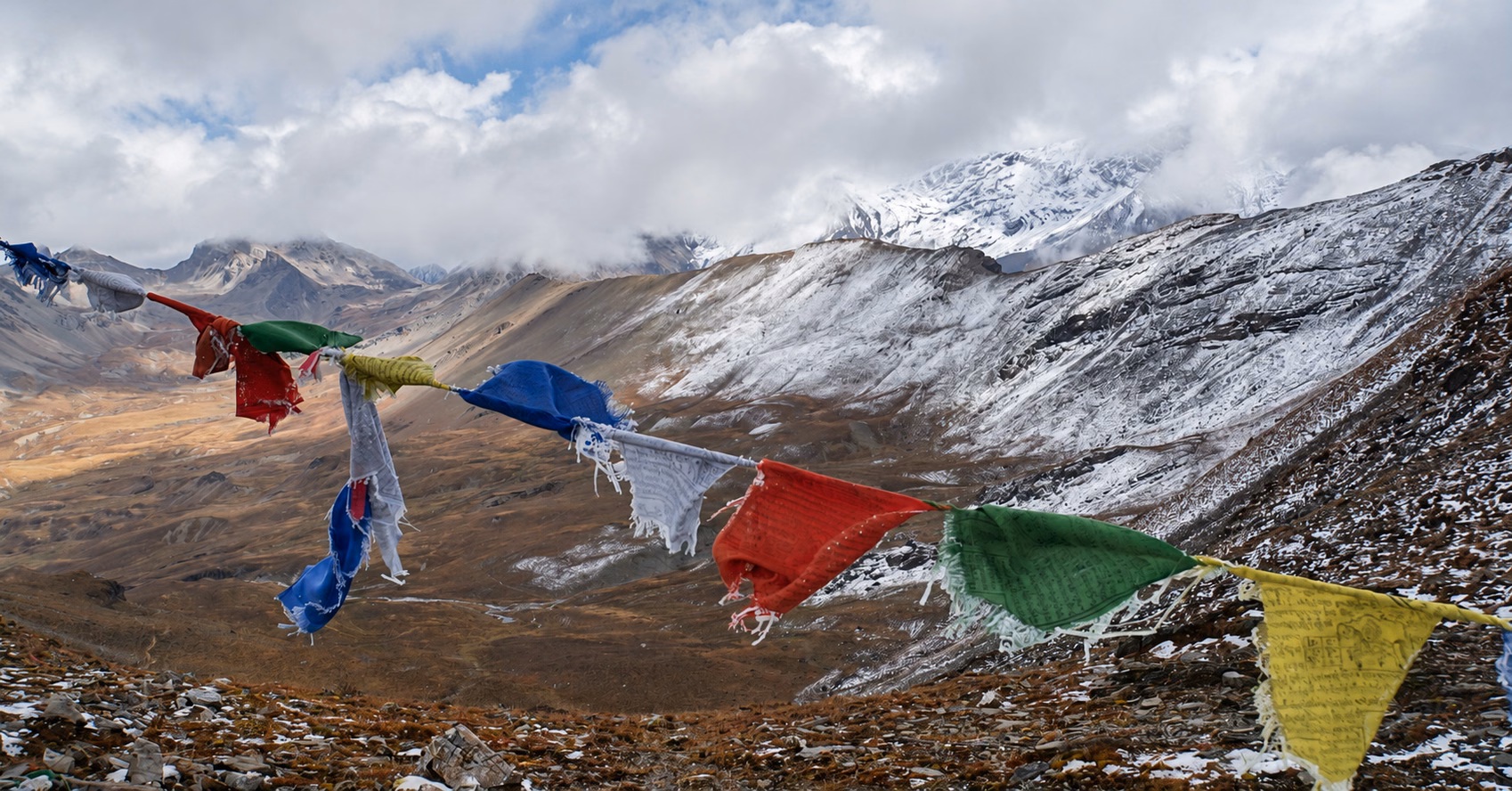 Prayer flags above snow-dusted mountain slopes on the Soi Yaktsha trekking loop in Bhutan