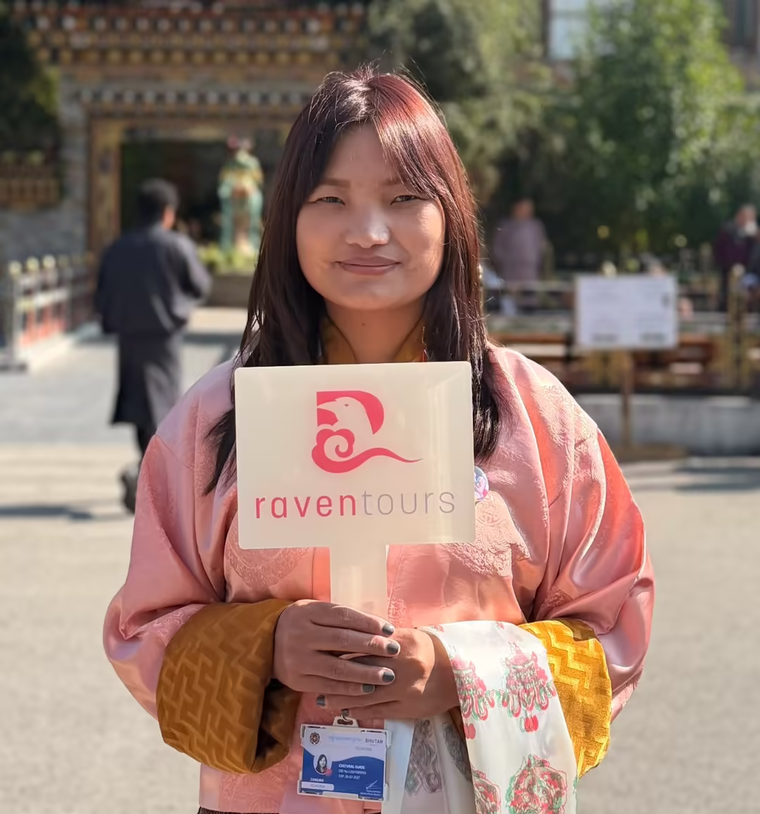 Raven Tours guide holding a welcome placard at Paro airport