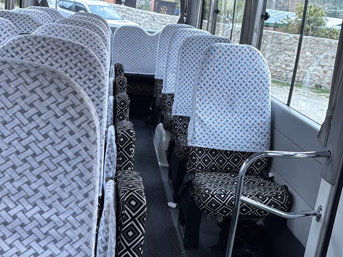 Toyota Coaster passenger cabin with patterned seats and a central aisle.