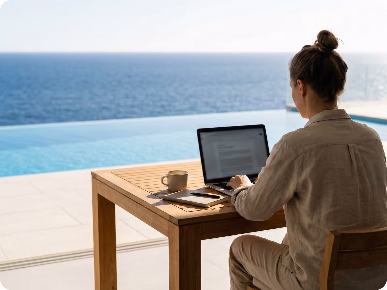 Professional working on a laptop by the ocean, illustrating flexible, location-independent invoicing and payments with xMoney.