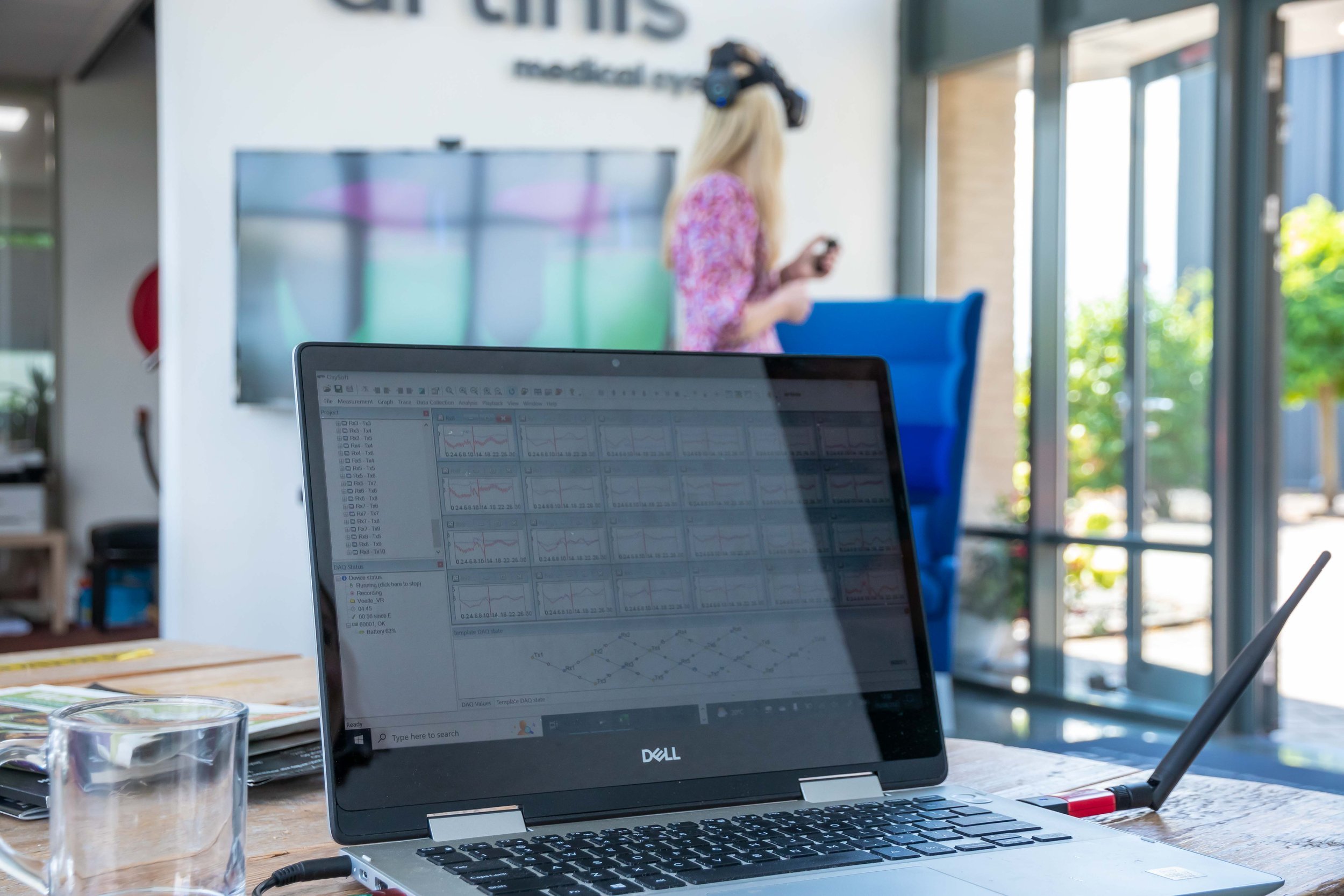 Laptop displaying Artinis fNIRS data analysis software next to a VR headset session