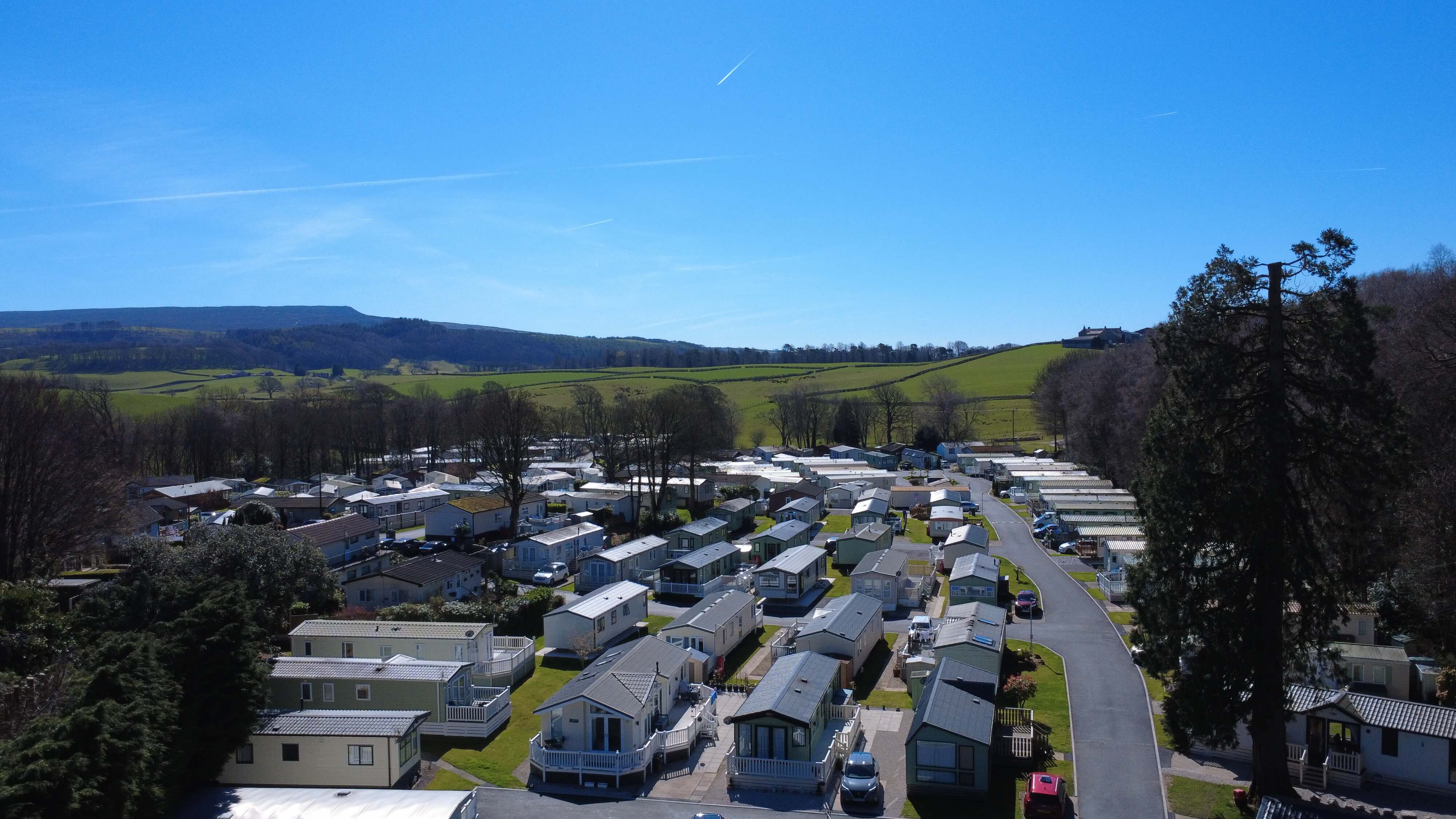 Mobile home park nestled in green countryside with hills and blue sky