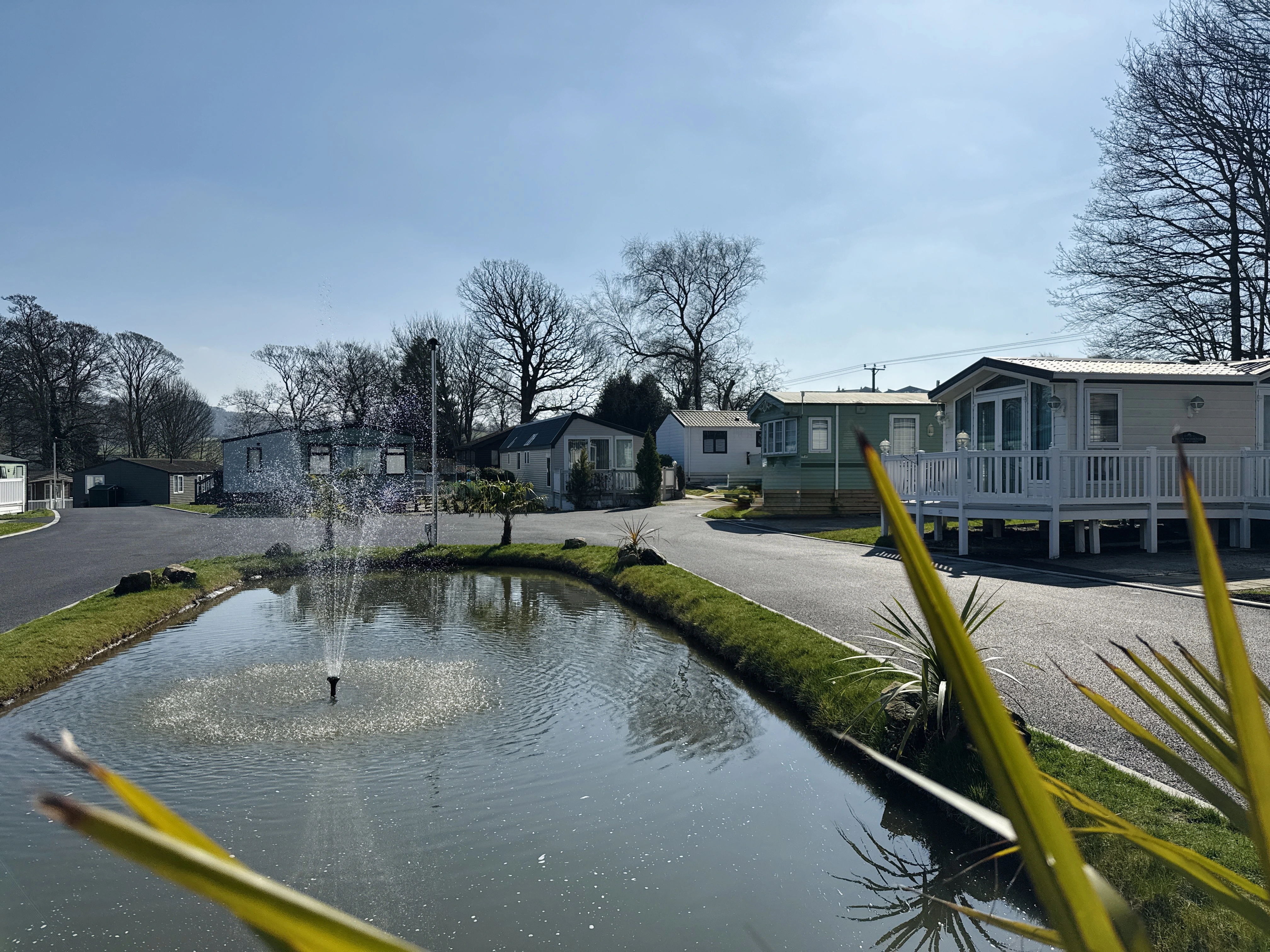 Tranquil mobile home park with fountain, leafless trees, and modern cabins
