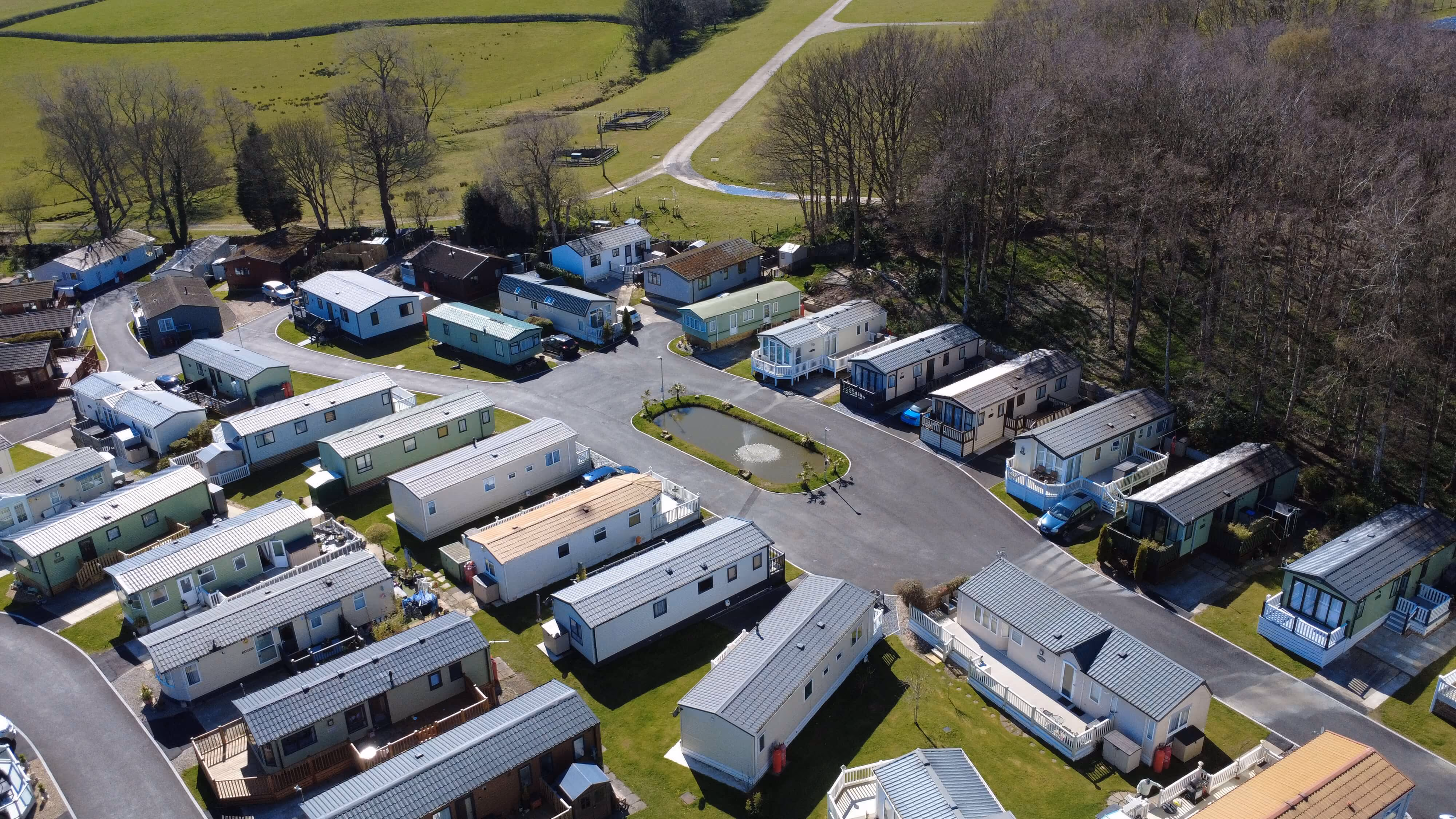 Aerial view of mobile home park with green fields and trees