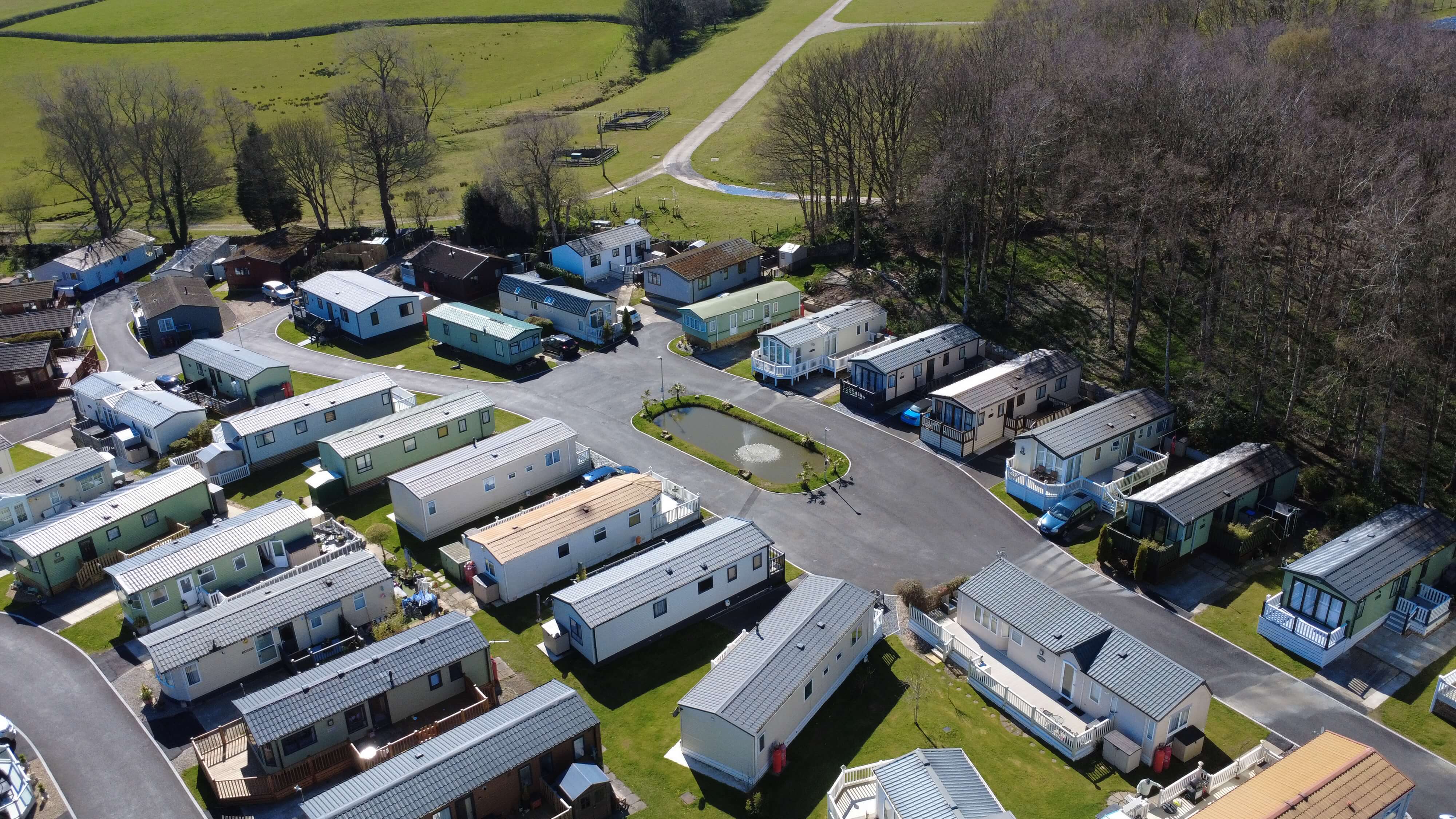 Aerial view of mobile home park with green fields and trees