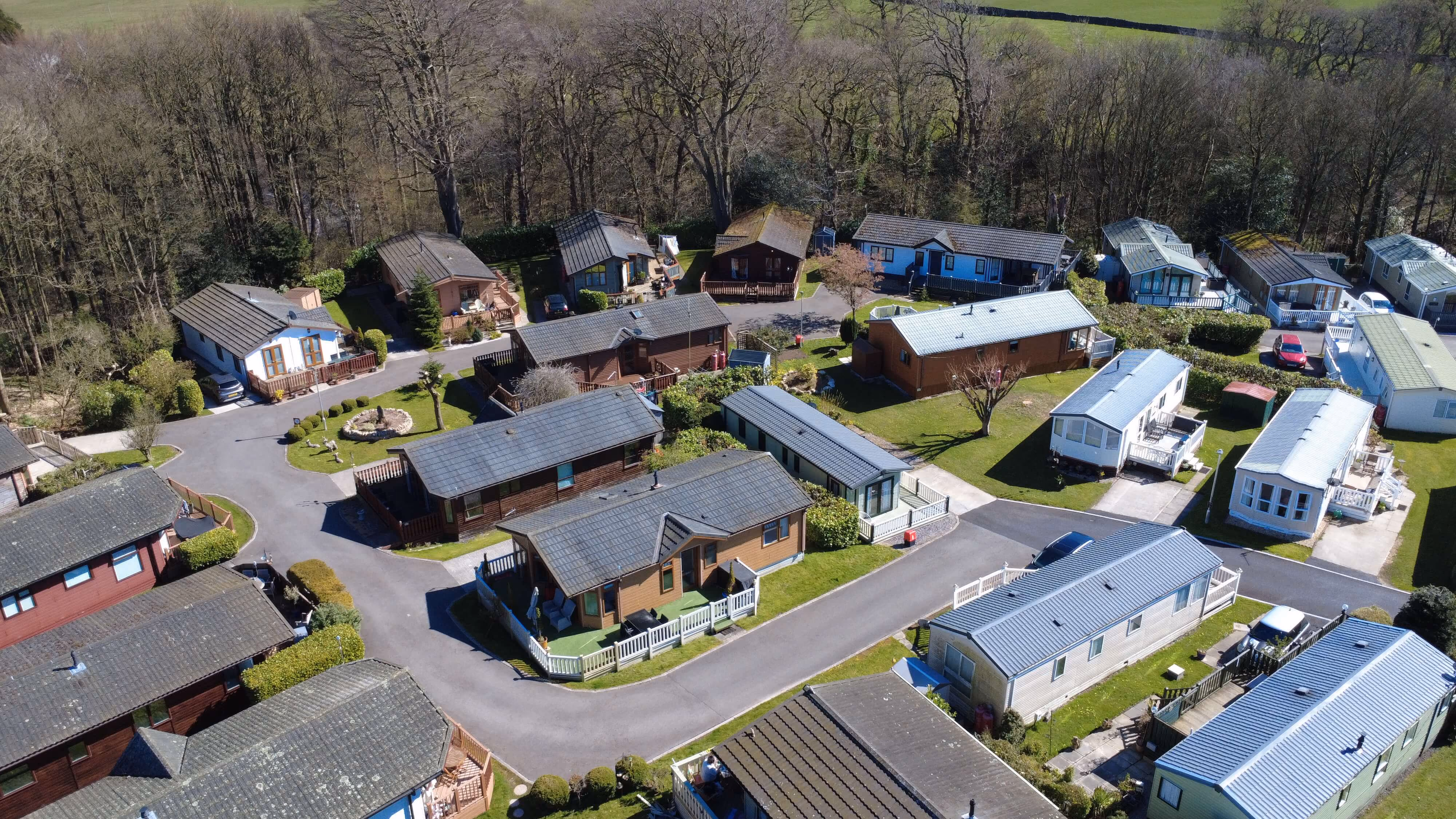 Aerial view of holiday park with colorful lodges nestled in wooded landscape