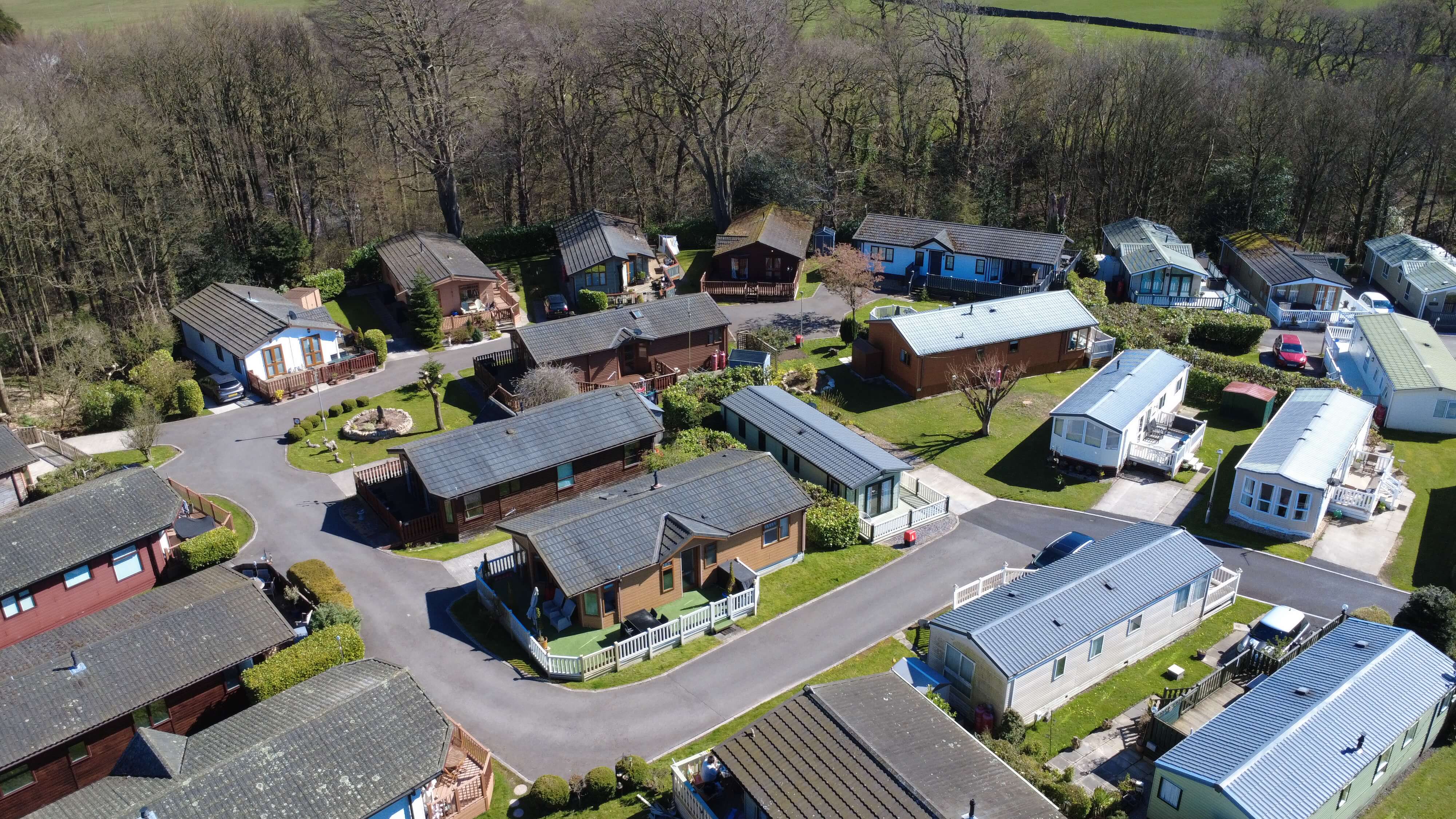 Aerial view of holiday park with colorful lodges nestled in wooded landscape