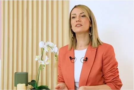 A woman standing in front of a vase with flowers.