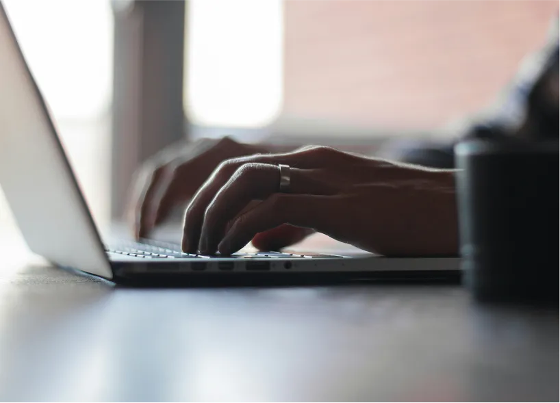 A person typing on a laptop on a table.