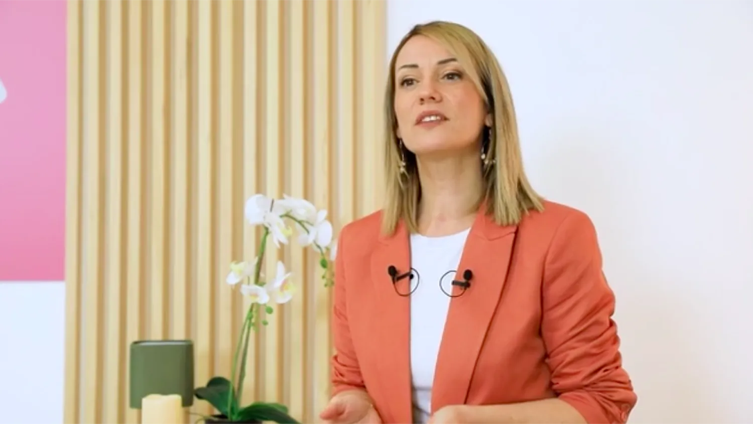 A woman standing in front of a vase with flowers.