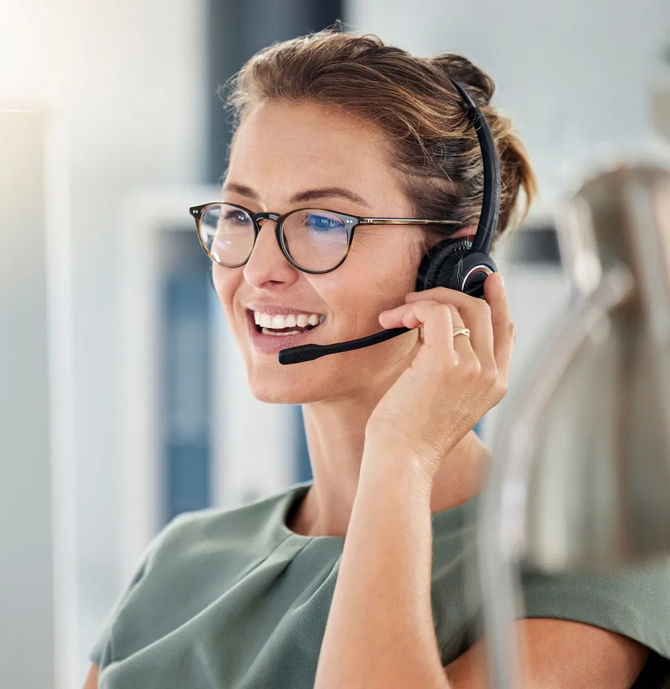 A woman wearing glasses talking on a headset.