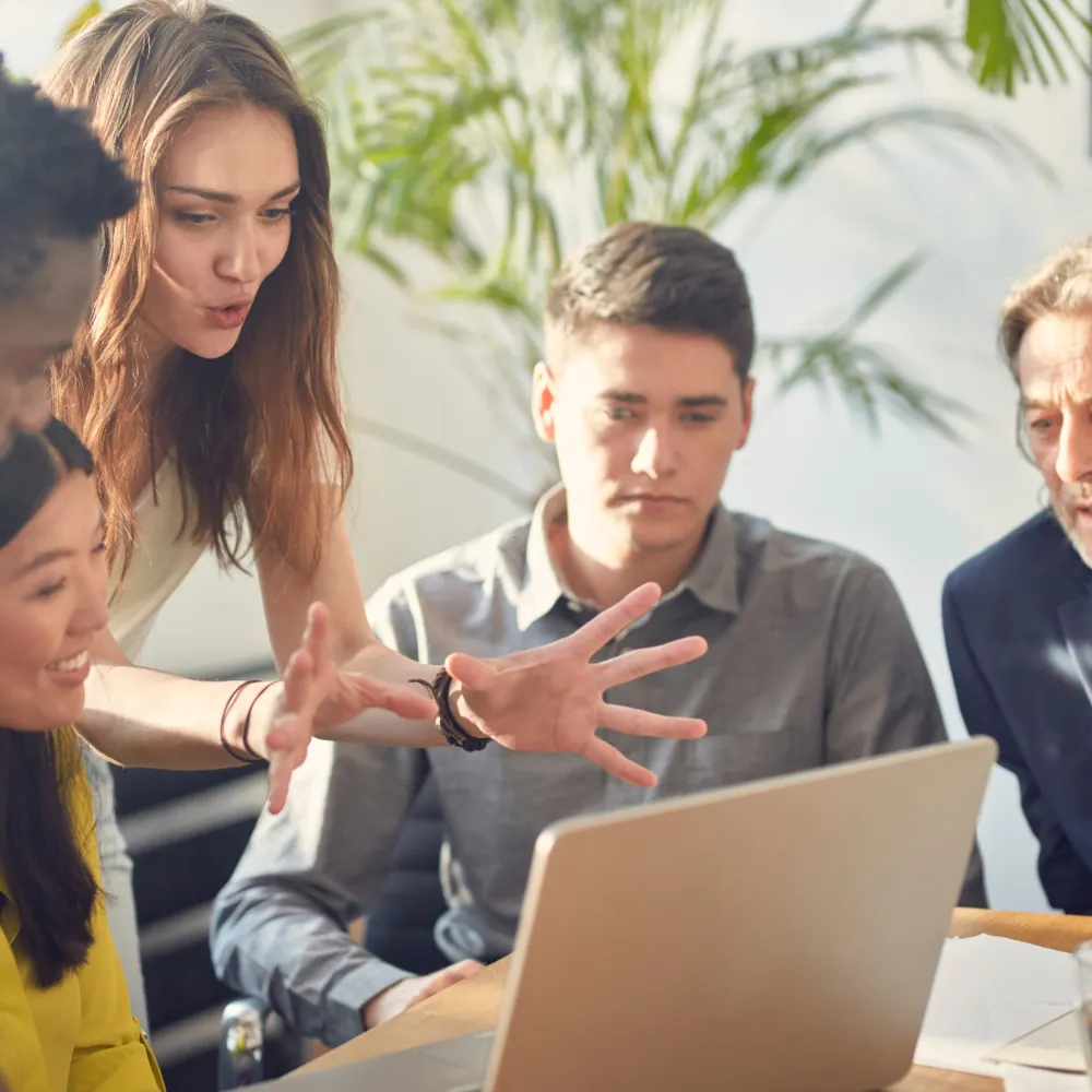 A group of people sitting around a laptop computer.