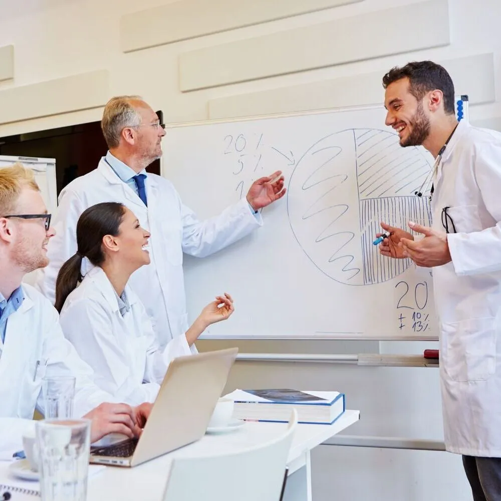 A group of people standing around a white board.