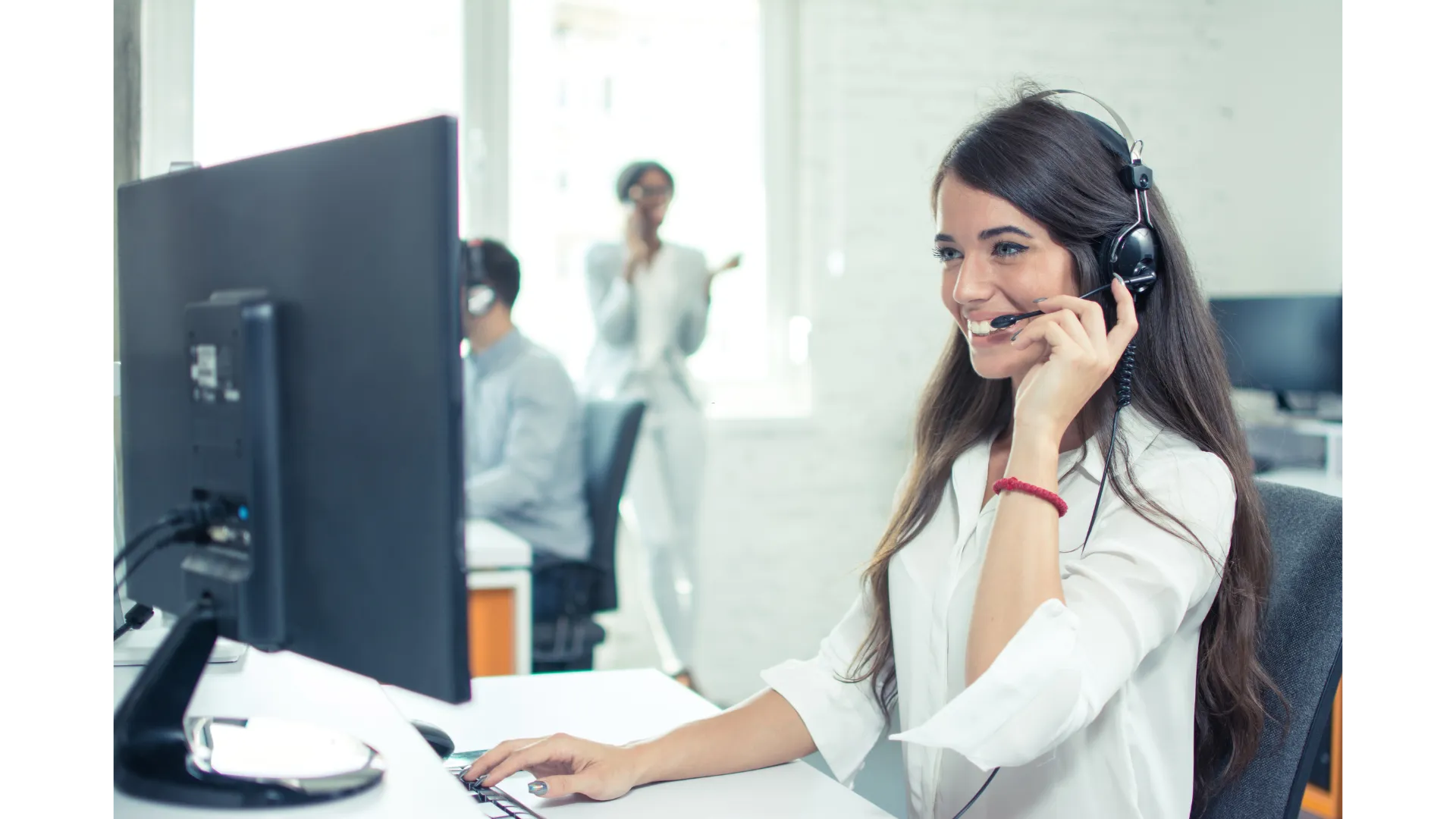 A woman sitting in front of a computer talking on a phone.