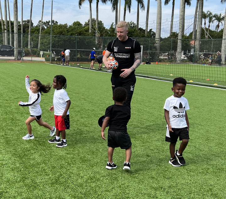 Youth soccer coach encouraging a child during training session.