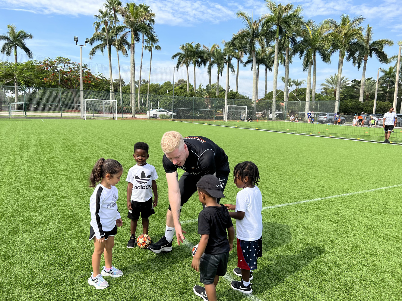 Kids aged 4–12 practicing soccer drills outdoors in a fun, safe environment.
