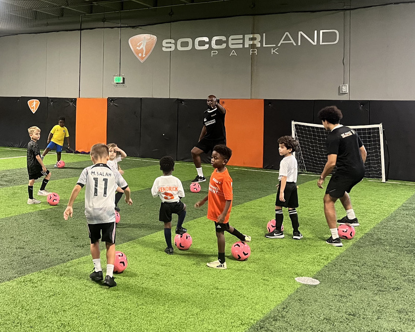 Group of children learning soccer with energetic coaching support.