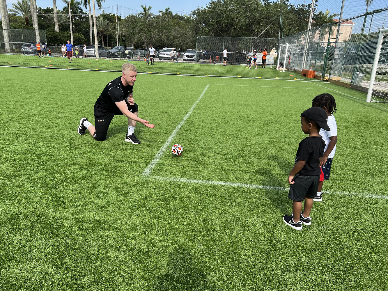 Youth soccer players standing together with coaches in a sunny field.