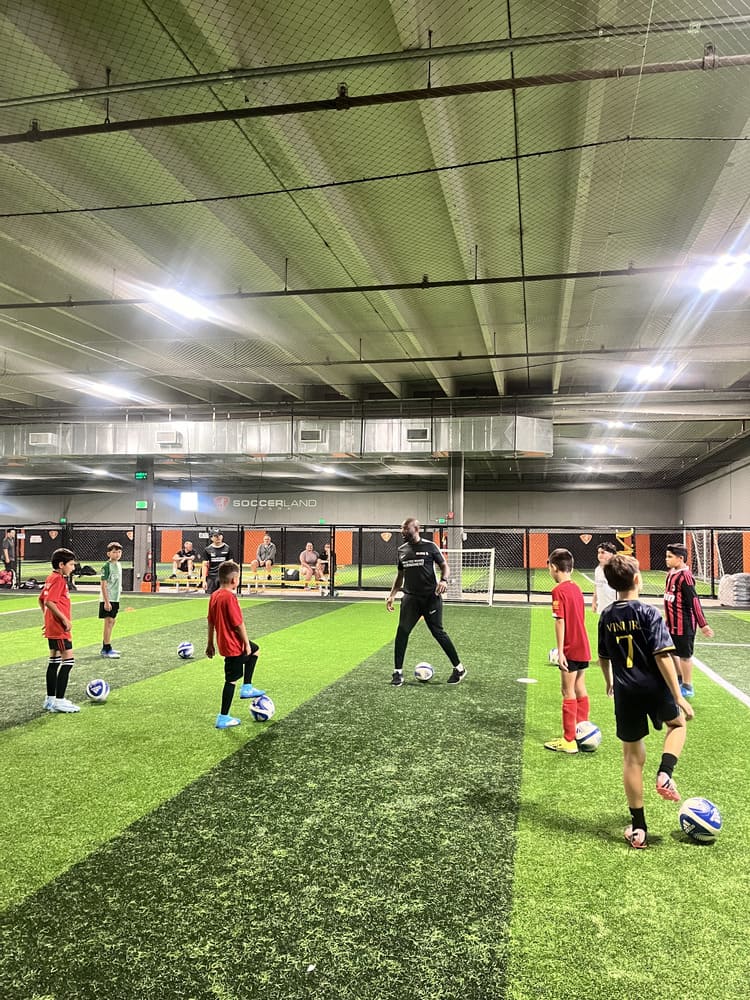 Friendly soccer coach supporting a child  in training session.