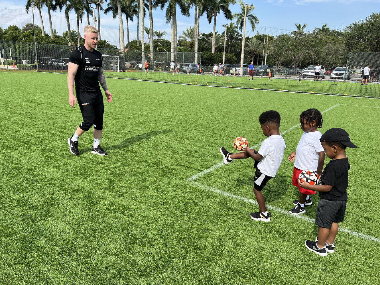 Football instructor giving personalised support to children in a youth programme