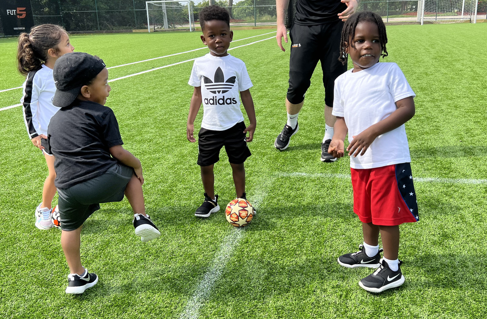Soccer coach supporting a young player during skill training.