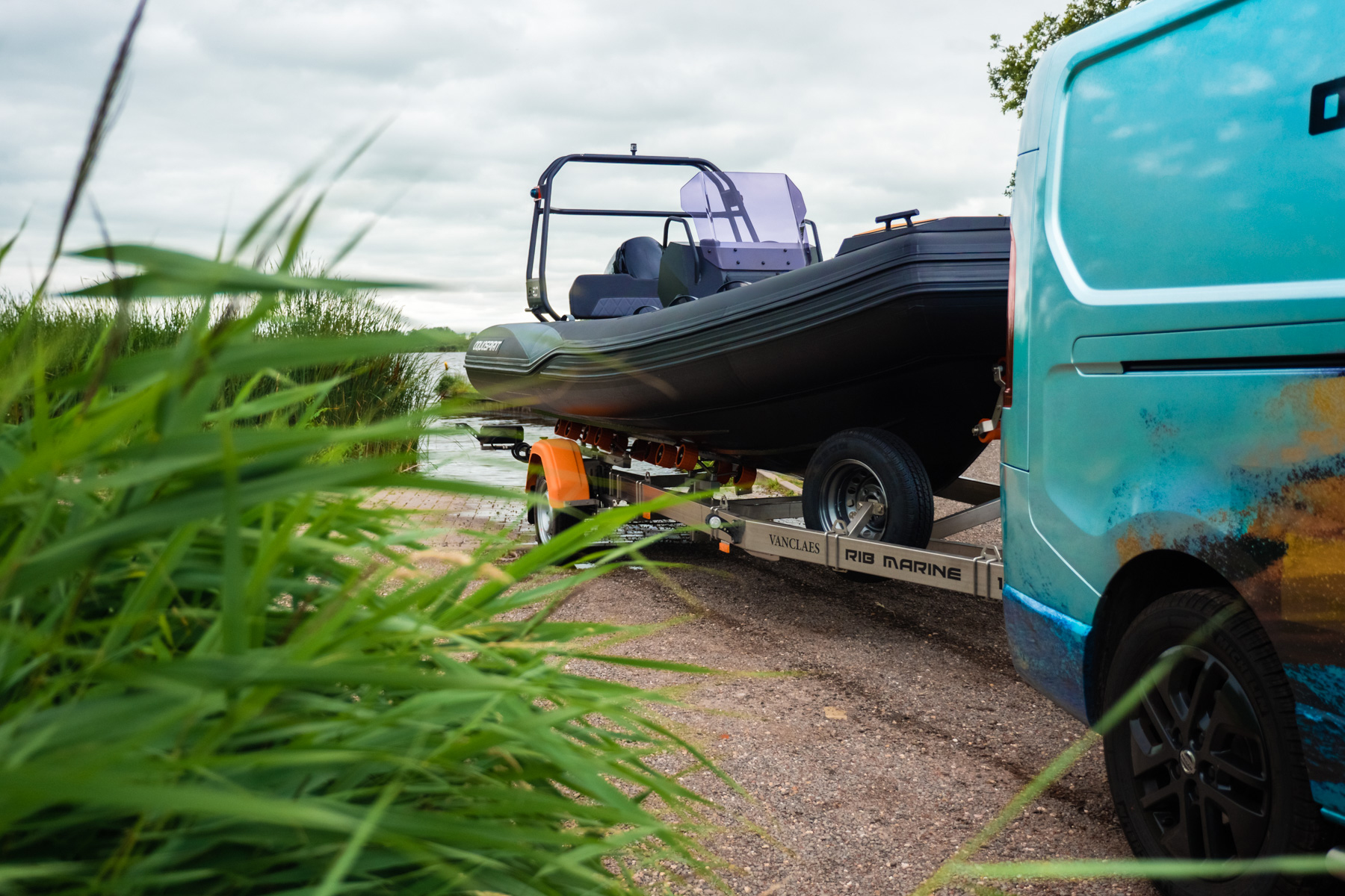 Aquaspirit RIB on a galvanized roller trailer at a slipway, hitched to a van