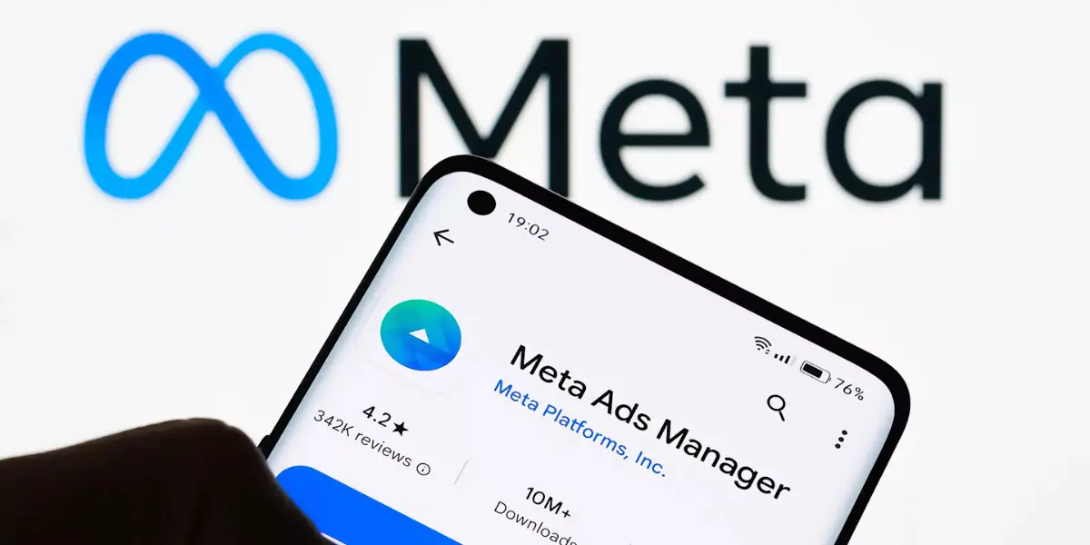 Application Meta Ads Manager sur smartphone devant logo Meta — gestion de publicités Facebook et Instagram en Valais par l'Agence 1872