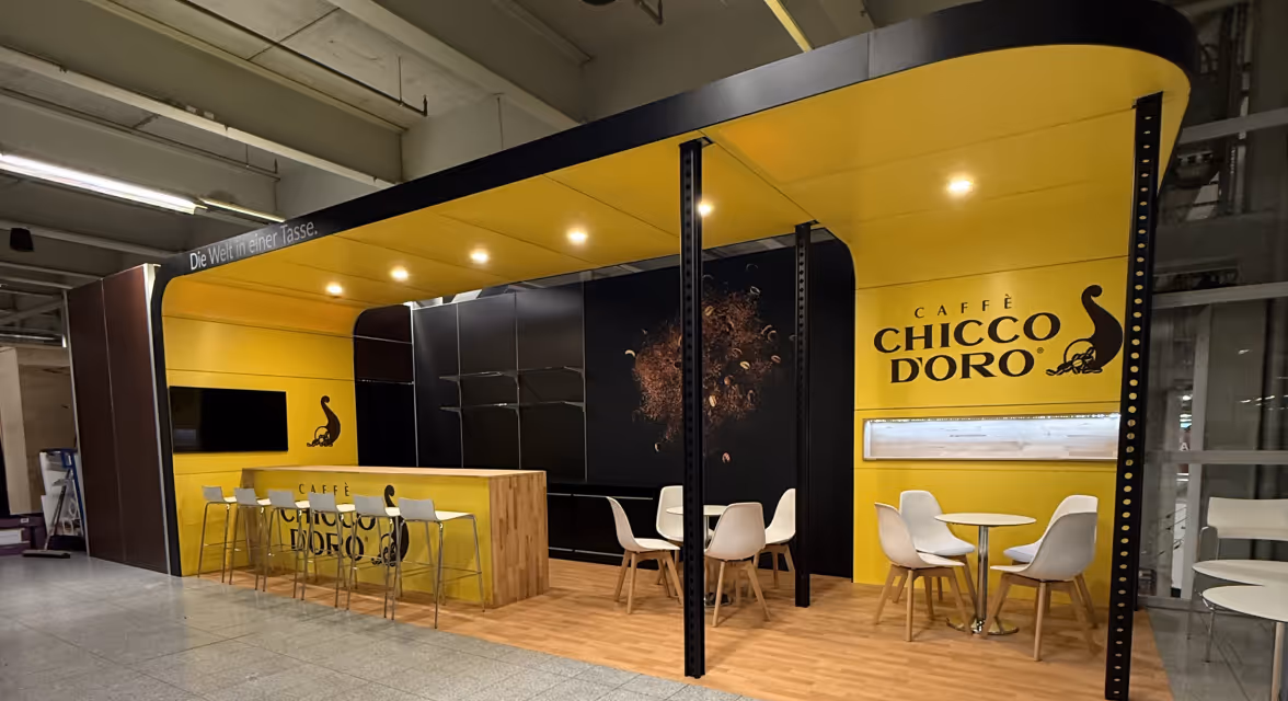 Ein gelber Messestand von Chicco Doro mit schwarzen Elementen.