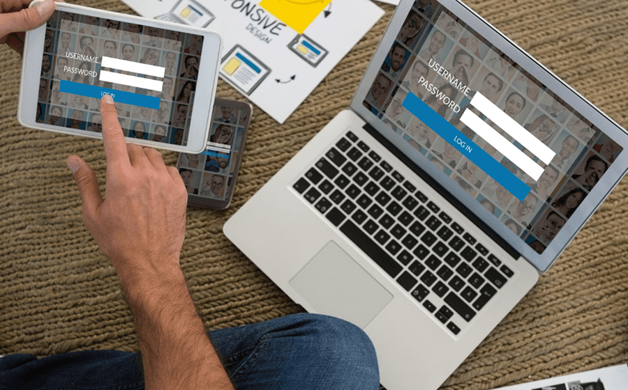 Person using a tablet and laptop to work on a website layout design.