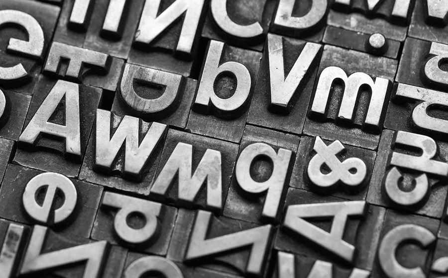 Black-and-white close-up of metal letterpress printing blocks.
