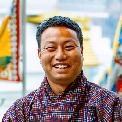 Portrait of Khenrab, Raven guide in checkered gho, showcasing warmth and cultural pride.