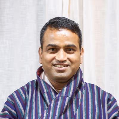 Portrait of Keshab, Raven guide in blue striped gho, reflecting welcoming spirit and expertise.