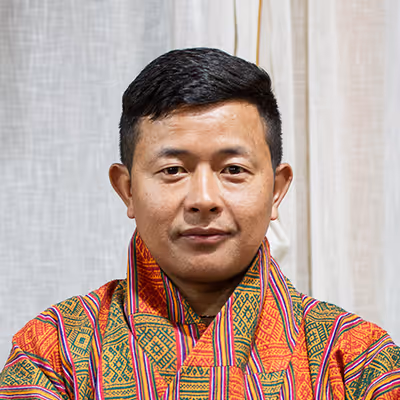 Portrait of Drona, Raven chauffeur in colorful gho, reflecting calm professionalism and care.