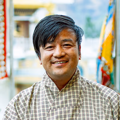 Portrait of Collen, Raven chauffeur in checked gho, sharing a friendly and welcoming presence.
