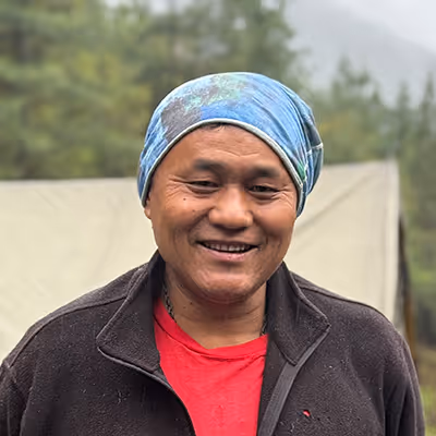 Portrait of Jigme, Raven trekking chef outdoors, smiling warmly and representing culinary hospitality.
