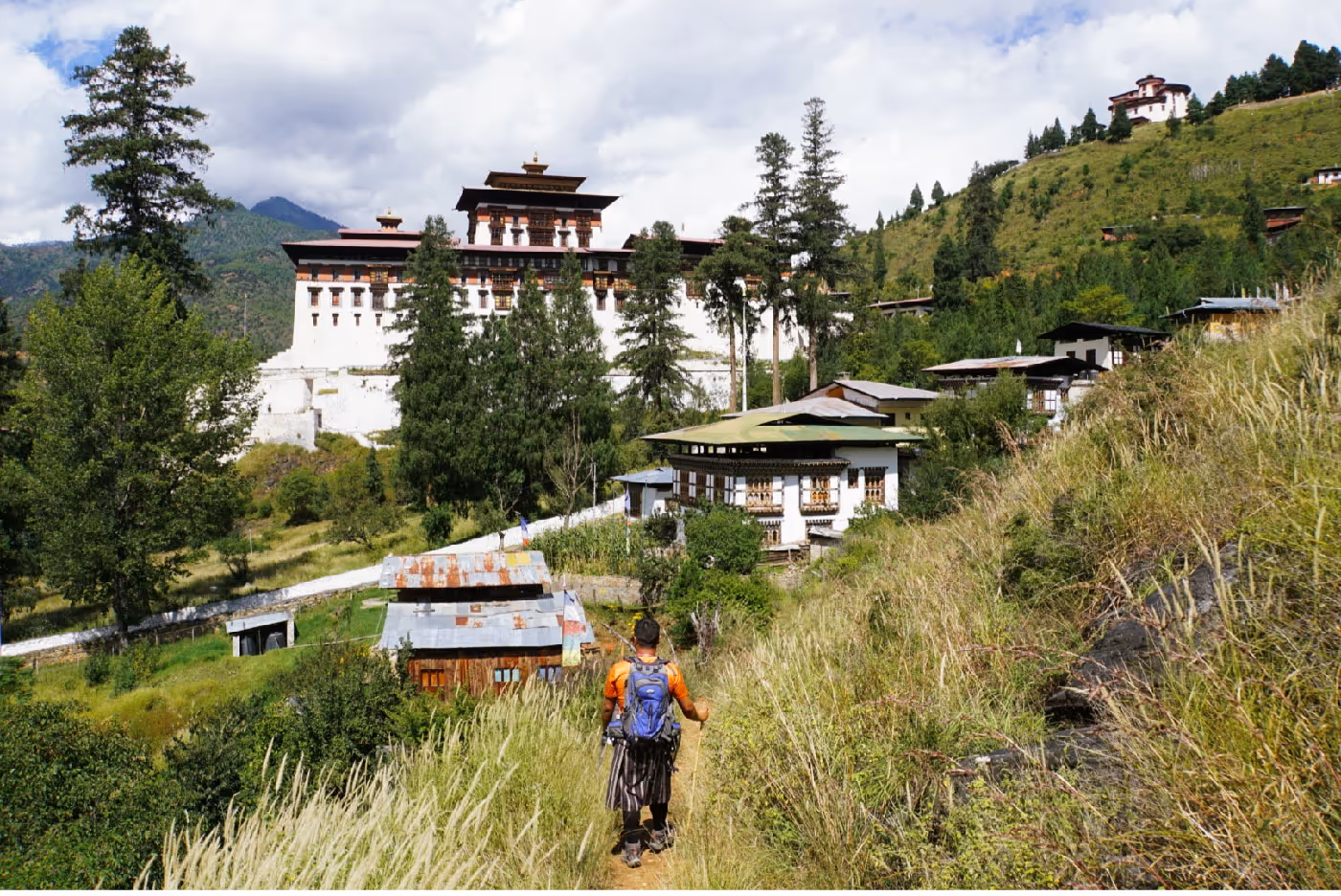 Local guide walks through tall grass toward historic Zuri Dzong, blending nature, heritage, and cultural immersion.
