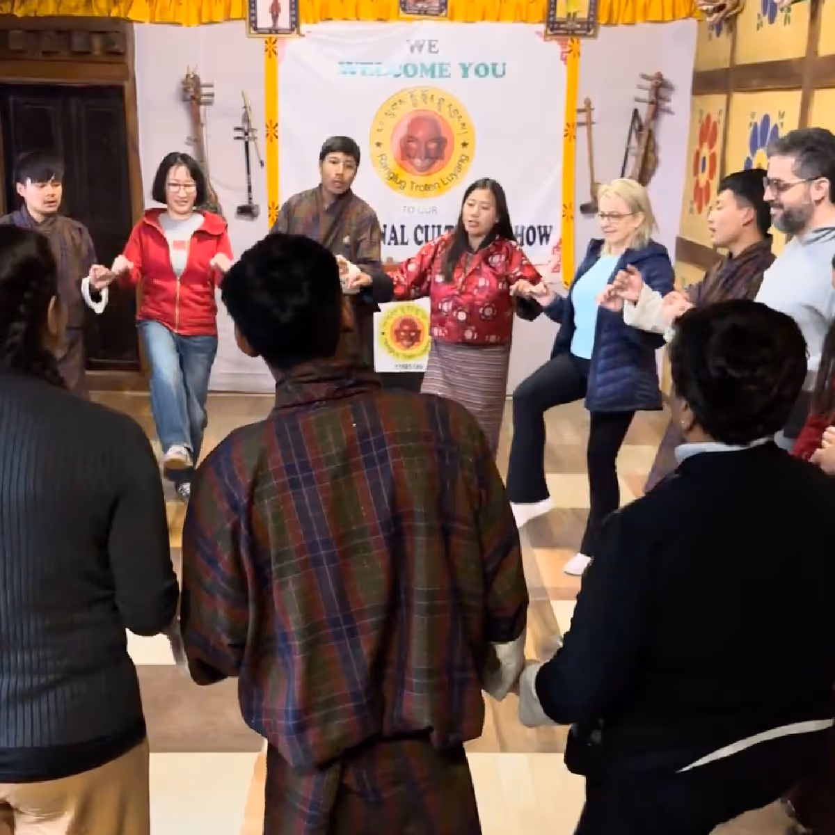 Raven Tours guests join hands with local Bhutanese performers in a joyful circle dance during a traditional cultural evening.